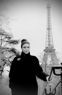 a black and white photo of a woman in front of the eiffel tower